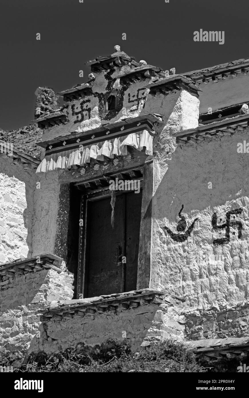 DAS UMGEKEHRTE HAKENKREUZ & SONNE & MOND schmücken eine Tür im Dorf GONGGAR - ZENTRUM VON TIBET Stockfoto