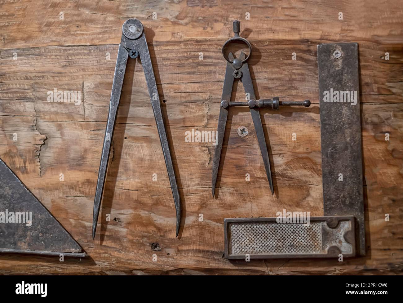Antike Zimmermannswerkzeuge auf einem Holz, antiker Kompass zum Nachzeichnen und ein Quadrat für Holzkanten, alte Zeichengeräte, horizontal Stockfoto