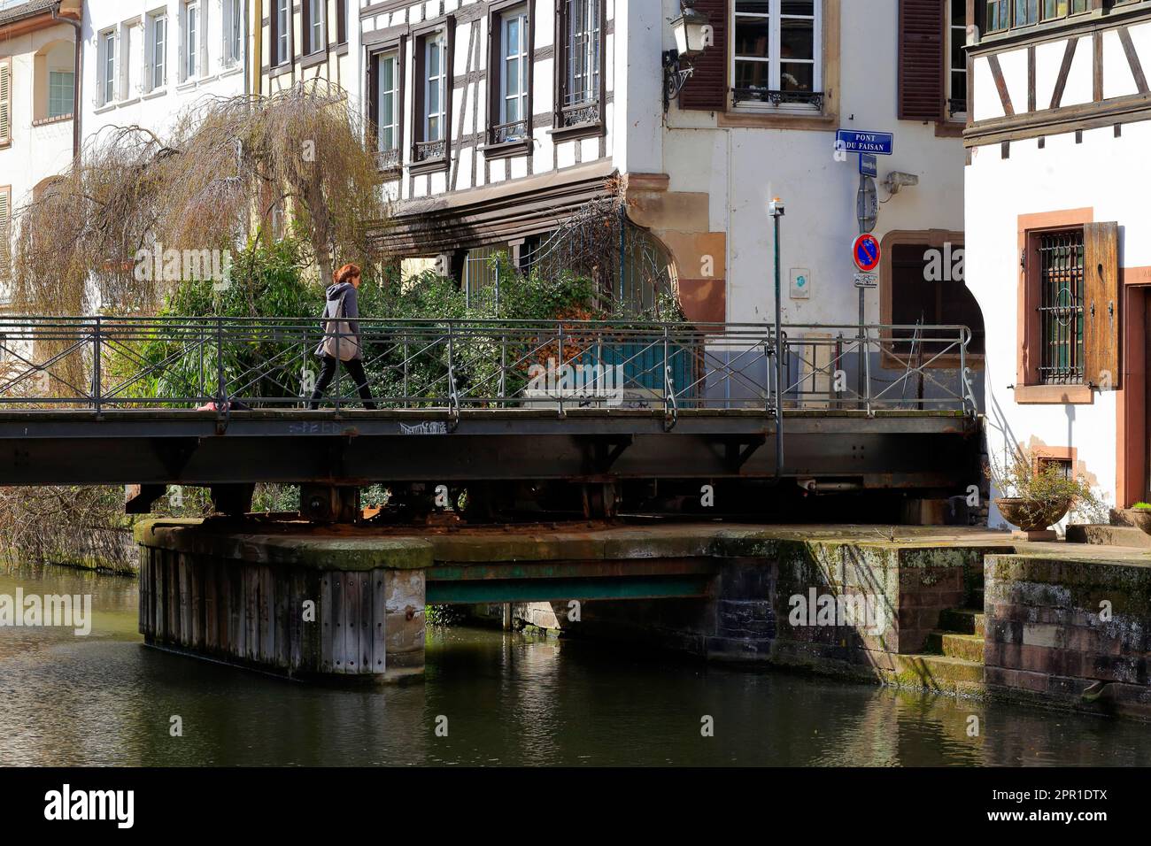 Eine Person geht über die Pont du Faisan, eine Hydraulik- oder Schwingbrücke über den Fluss Ill in Grande-Île de Strasbourg, Frankreich. Stockfoto