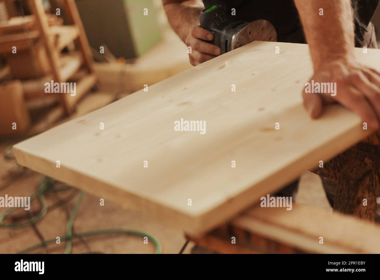 Zimmermann bei der Arbeit mit einem modernen Schleifgerät. Ein kleines Werkzeug, das Schleifpapier mit hoher Geschwindigkeit mit der Präzision und Kontrolle bewegt, die der Handwerker gerne vermitteln möchte. Stockfoto