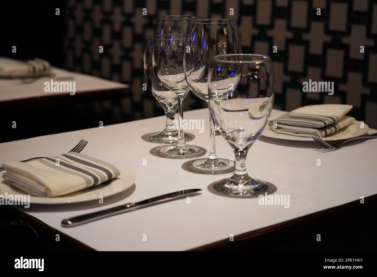 Schwach beleuchteter Restauranttisch mit Weingläsern für zwei Personen Stockfoto