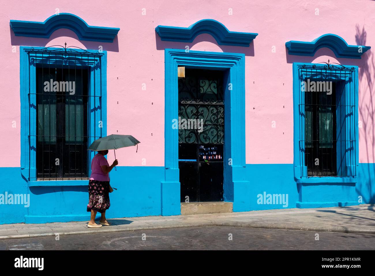 Straßenszene, historisches Zentrum, Oaxaca Mexico. Fußgänger, die sich mit einem Regenschirm vor verbrannter Hitze schützen Stockfoto