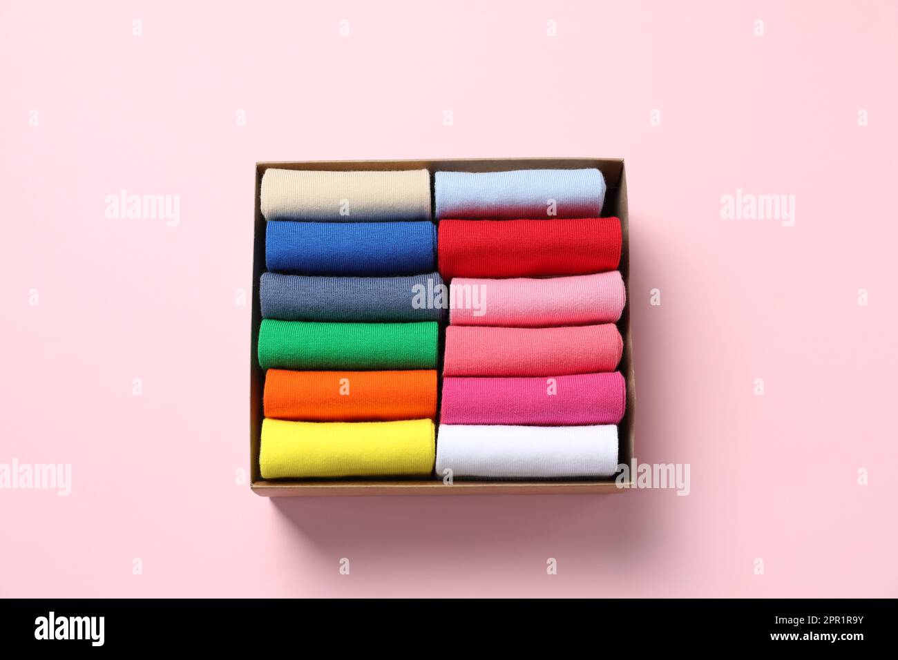 Box mit verschiedenen bunten Socken auf hellrosa Hintergrund, Draufsicht Stockfoto