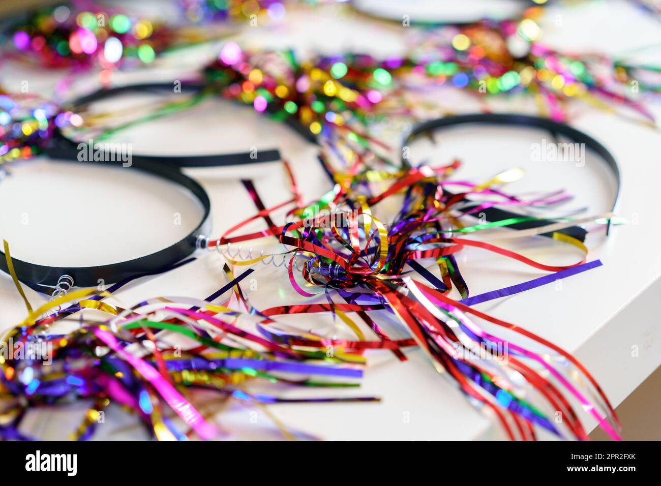 Festliche Stirnbänder mit Lametta zur Geburtstags- oder Partyvorbereitung. Farbenfrohe Stirnbänder bereit für Party. Festliche Bügel mit Lametta auf einem Tisch, perfekt für Geburtstage und besondere Anlässe. Stockfoto