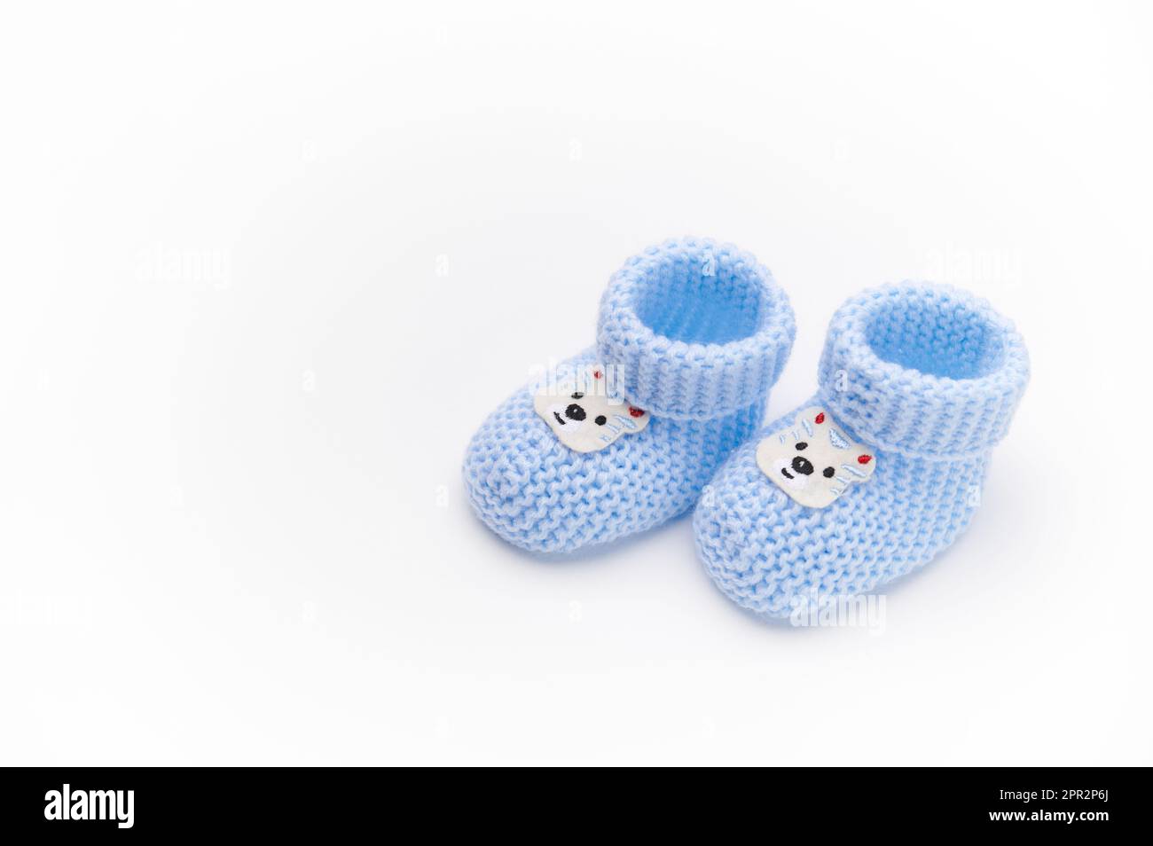 Ein Paar handgefertigte blaue gestrickte Babyschühchen, isoliert auf weißem Hintergrund. Neugeborenenbekleidung und Schwangerschaftskonzept. Kopierbereich für Werbetext. F Stockfoto