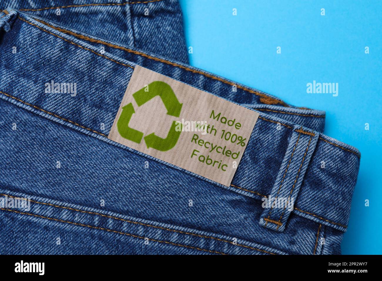 Jeans mit Recycling-Etikett auf hellblauem Hintergrund, Nahaufnahme Stockfoto