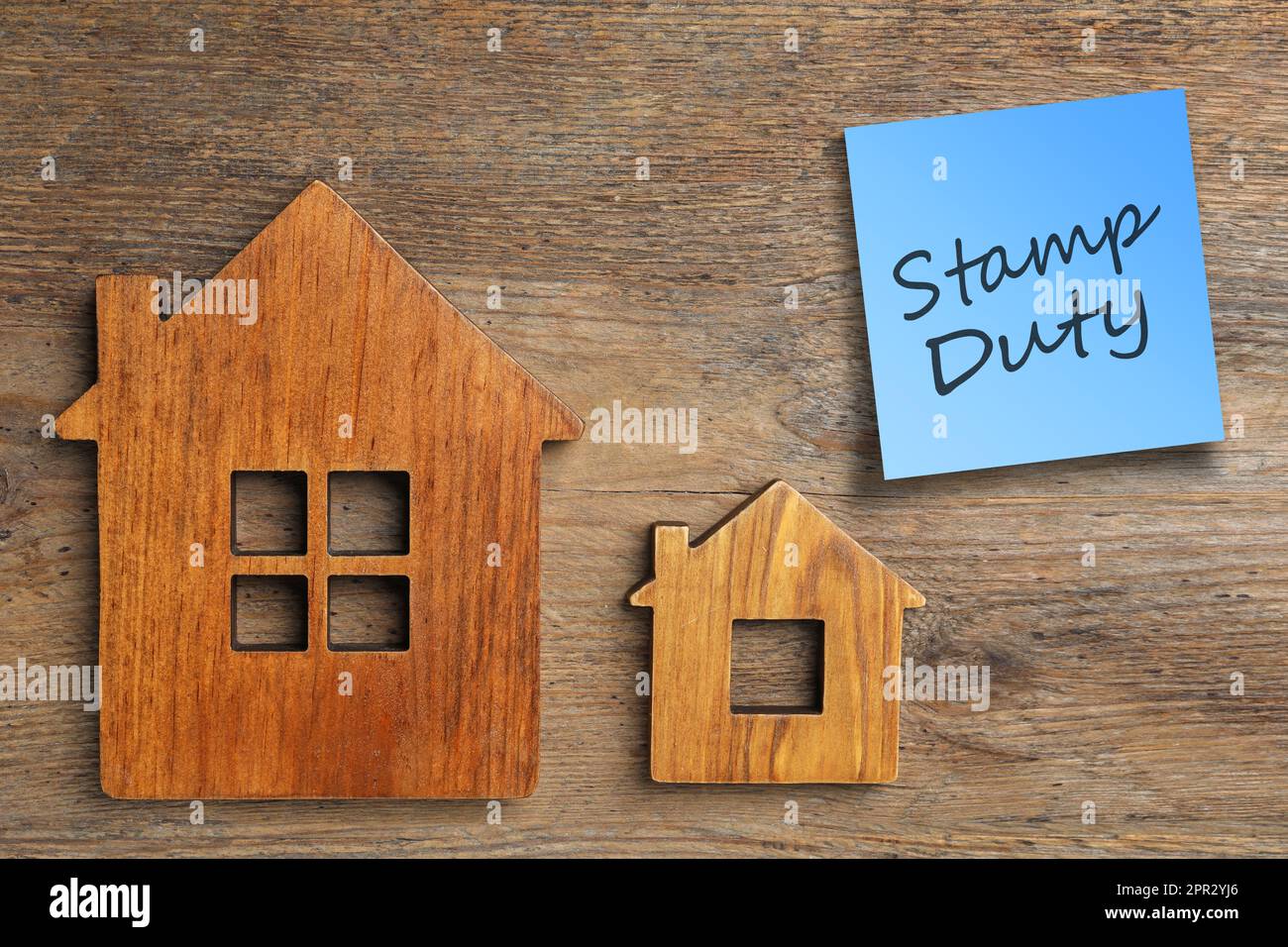 Hausfiguren und Haftnotiz mit Text Stamp Duty auf Holzhintergrund, flach liegend Stockfoto