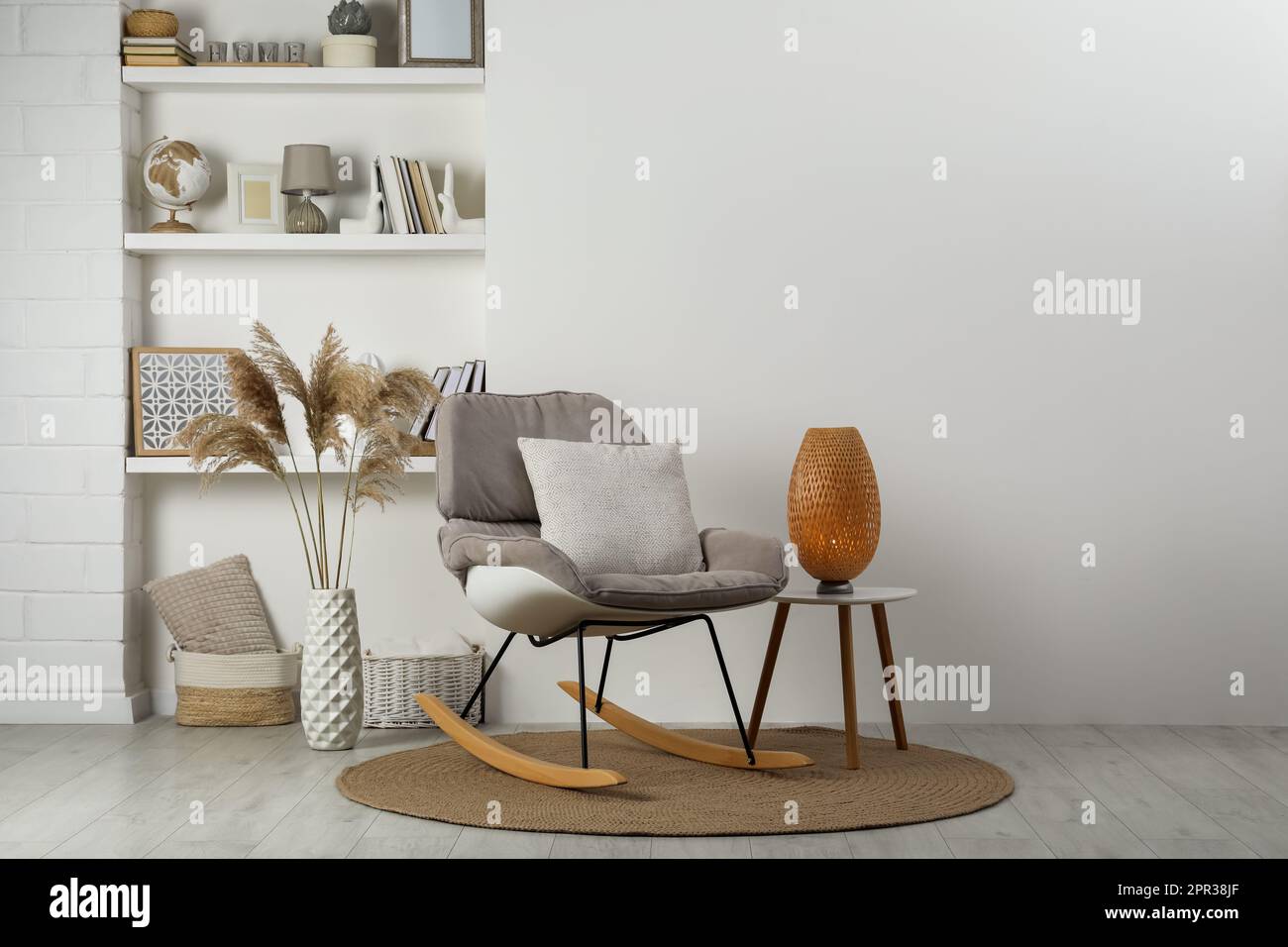 Weicher Schaukelstuhl mit Kissen auf Teppich nahe der Wand im Zimmer.  Innendesign Stockfotografie - Alamy
