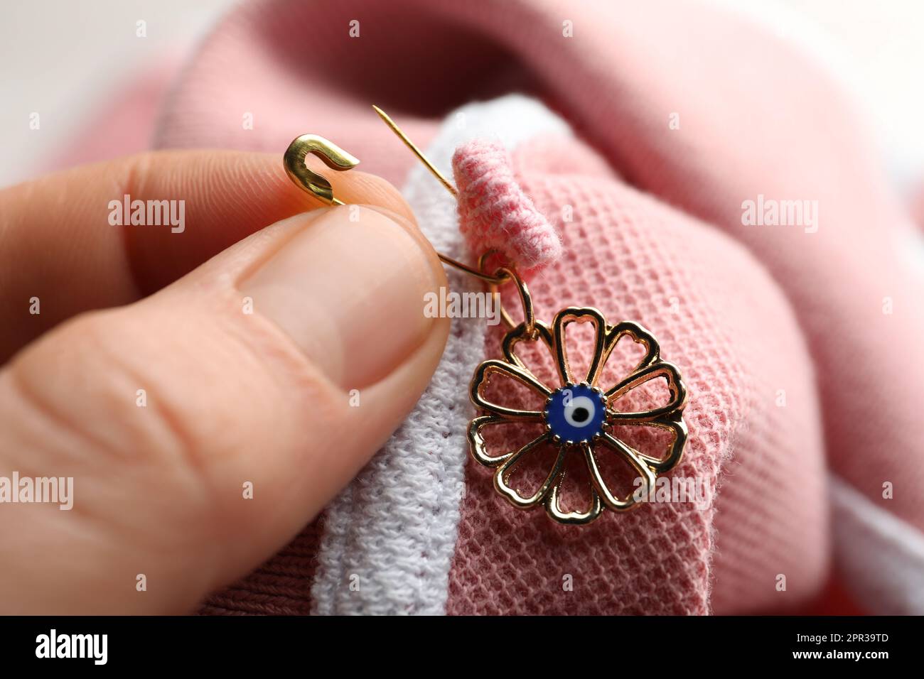 Eine Frau, die böse Augen-Amulett auf die Kleidung klebt, Nahaufnahme Stockfoto