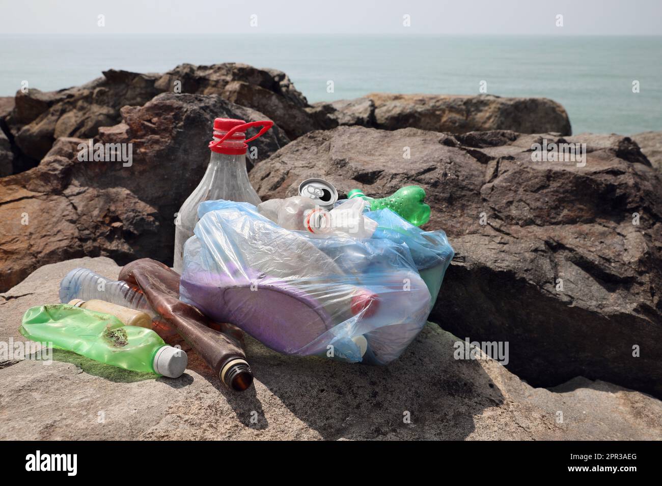 Müll auf Steinen in der Nähe des Meeres. Umweltverschmutzungskonzept Stockfoto