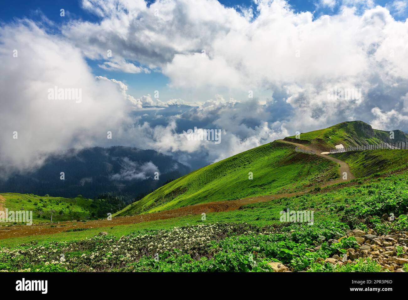 Atemberaubende Berglandschaft an einem sonnigen Sommertag mit bewölktem Himmel. Berge mit grünem Gras bedeckt mit Schnee vor einem bewölkten Himmel. Stockfoto