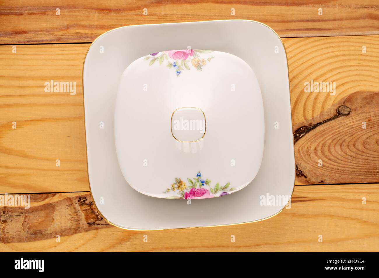 Eine alte Porzellanuntertasse für Butter auf einem Holztisch, Makro, Draufsicht. Stockfoto