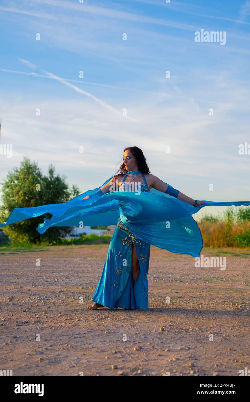 Orientalische Tänzerin in Blau mit Isis-Flügeln der gleichen Farbe, die draußen tanzt Stockfoto