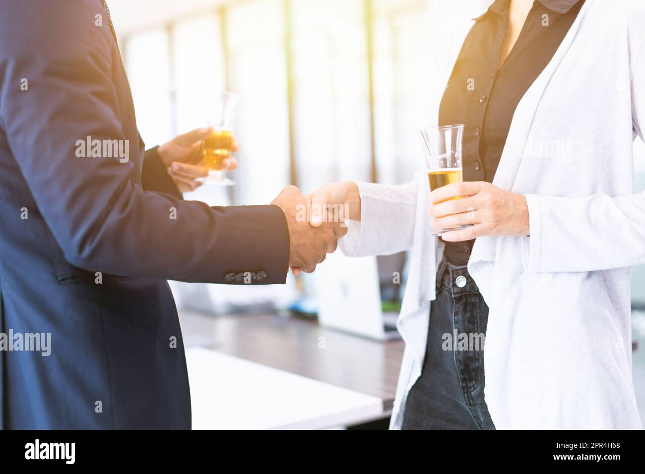 Geschäftsleute, die sich die Hände schütteln, treffen sich und trinken Weißwein auf einer Büroparty Stockfoto