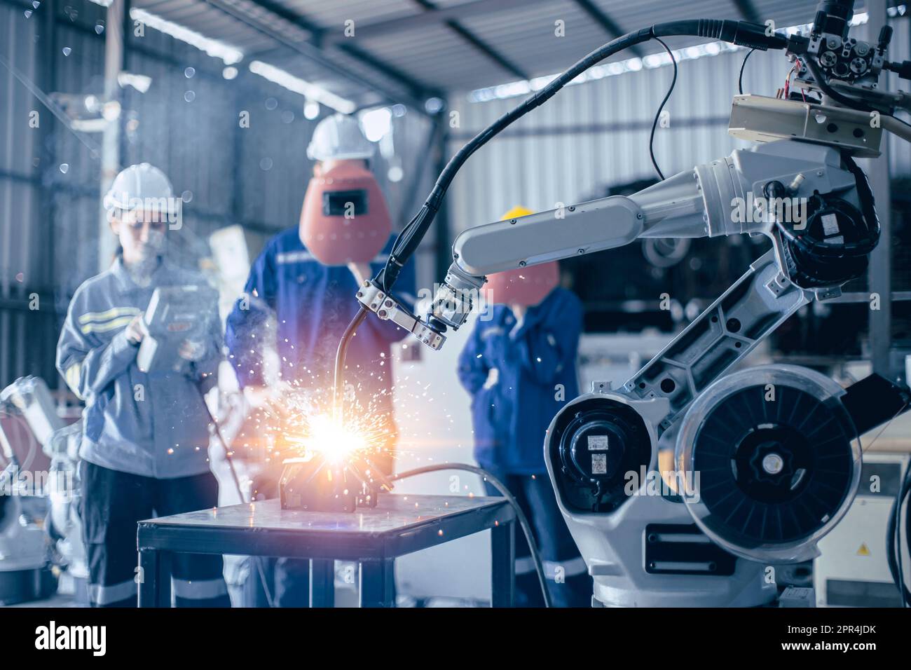 Die Arbeitssteuerung des Technikerteams bedient den kleinen Roboter-Schweißarm in der Metallwerkstatt Stockfoto
