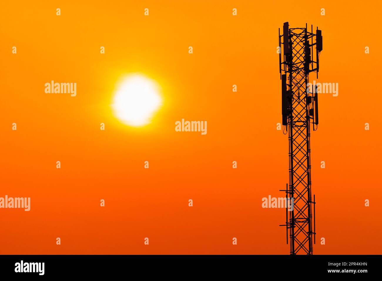 5G-Mobilfunkantenne für digitale Mobilfunkmasten auf klarem Hintergrund mit orangefarbenem Himmel bei Sonnenuntergang. Stockfoto