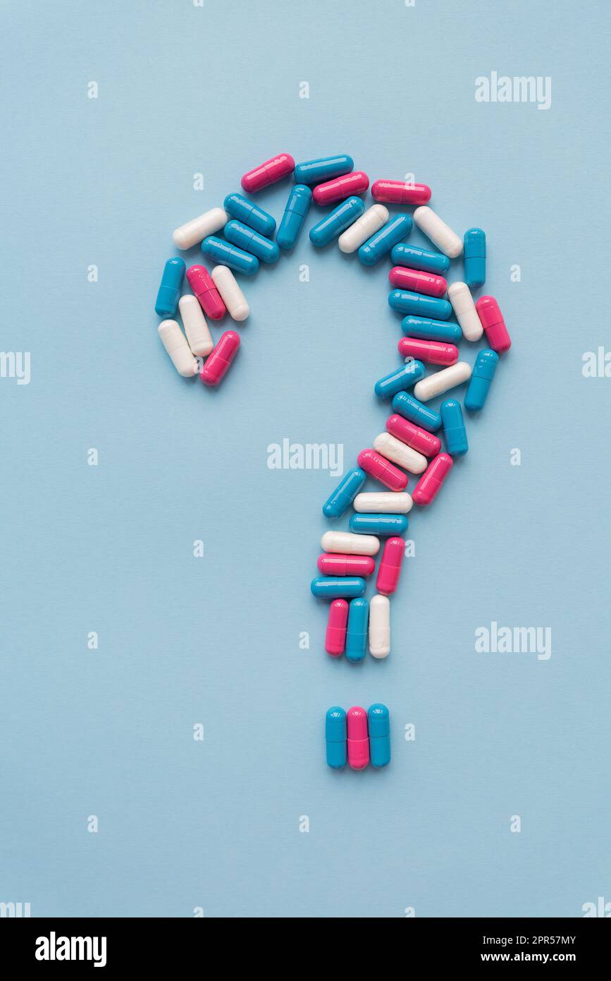 Fragezeichen bestehend aus drei mehrfarbigen Vitaminen auf blauem Hintergrund. Gesundheitsprobleme und Behandlung. Das Konzept der evidenzbasierten Medizin Stockfoto