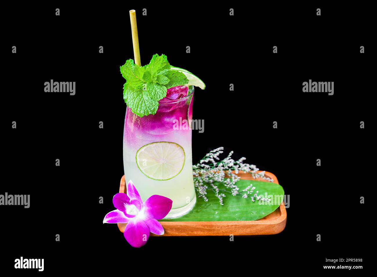 Limonade mit lila Sirup und Minze auf Holzplatte isoliert auf schwarzem Hintergrund Stockfoto
