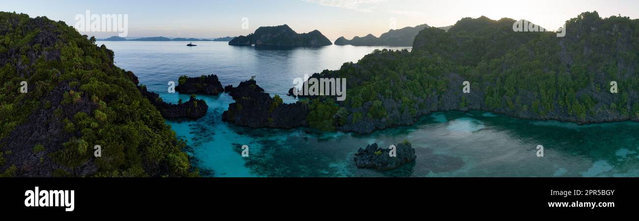 Am frühen Morgen scheint Licht auf die dramatischen Kalksteininseln, die sich aus Raja Ampats wunderschöner, biologischer und vielfältiger Meereslandschaft erheben. Stockfoto