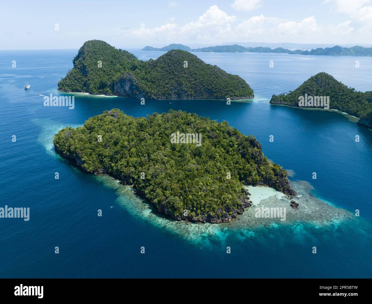 Wunderschöne und vielfältige Korallenriffe umgeben die dramatischen Kalksteininseln, die sich aus Raja Ampats vielfältiger Meereslandschaft erheben. Stockfoto