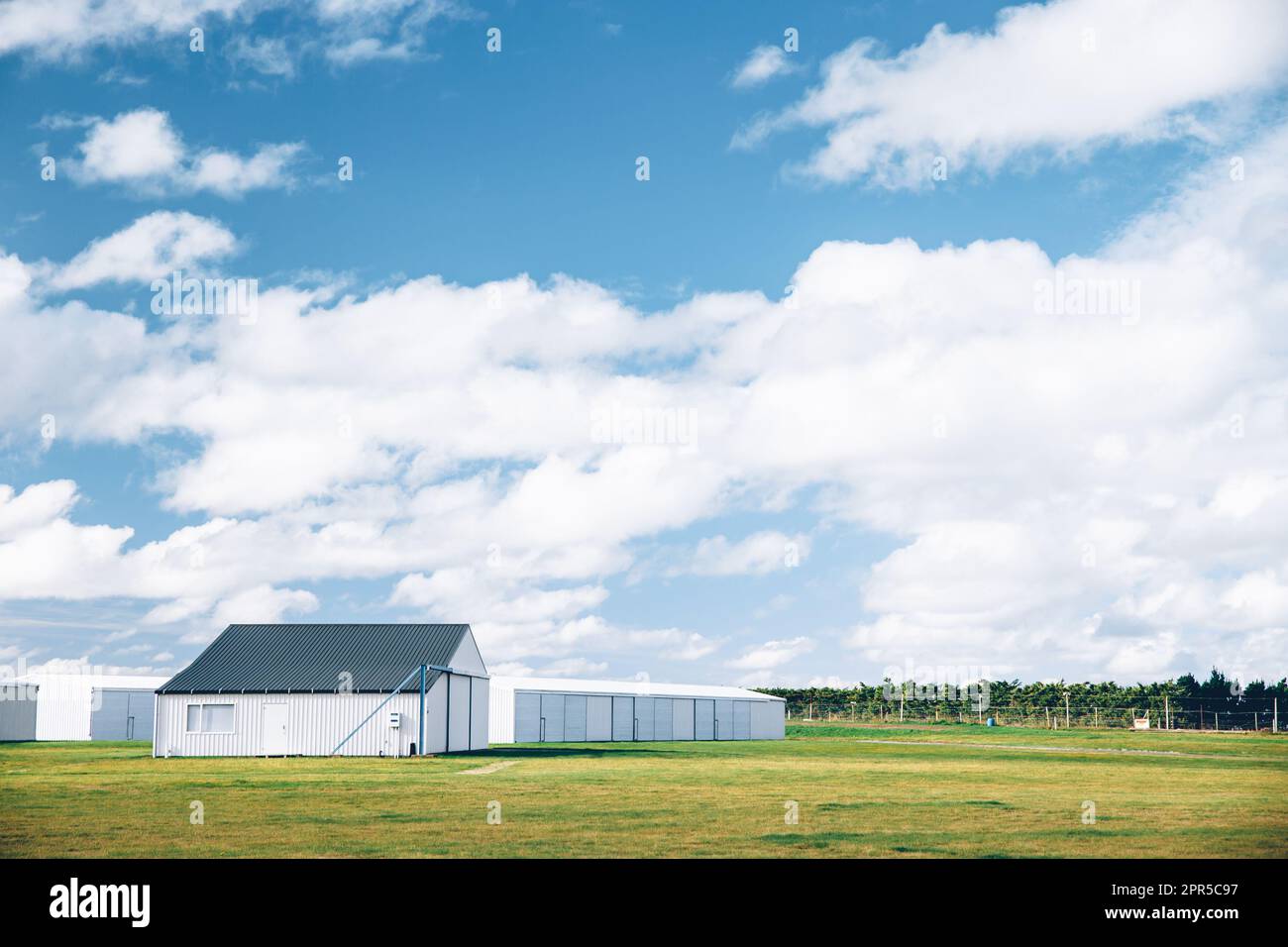 Stahlscheune auf einer Farm mit wolkenlosem blauen Himmel. Stockfoto