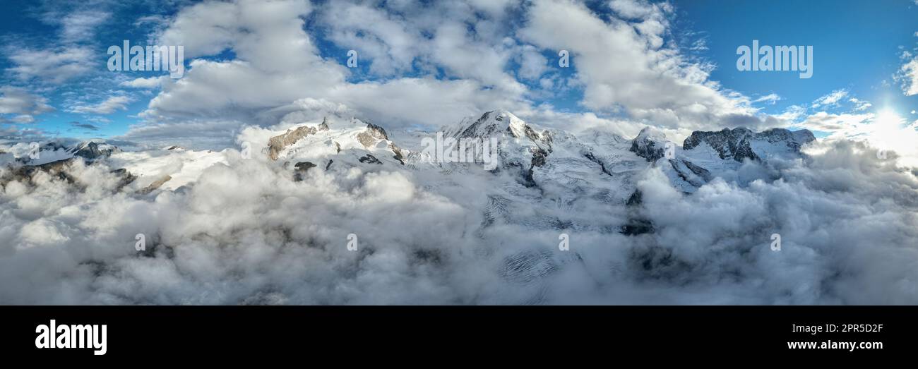 Panoramablick aus der Vogelperspektive auf den schneebedeckten Monte Rosa, Lyskamm, Pollux, Castor, Breithorn in einem Wolkenmeer, Zermatt, Wallis, Schweiz Stockfoto