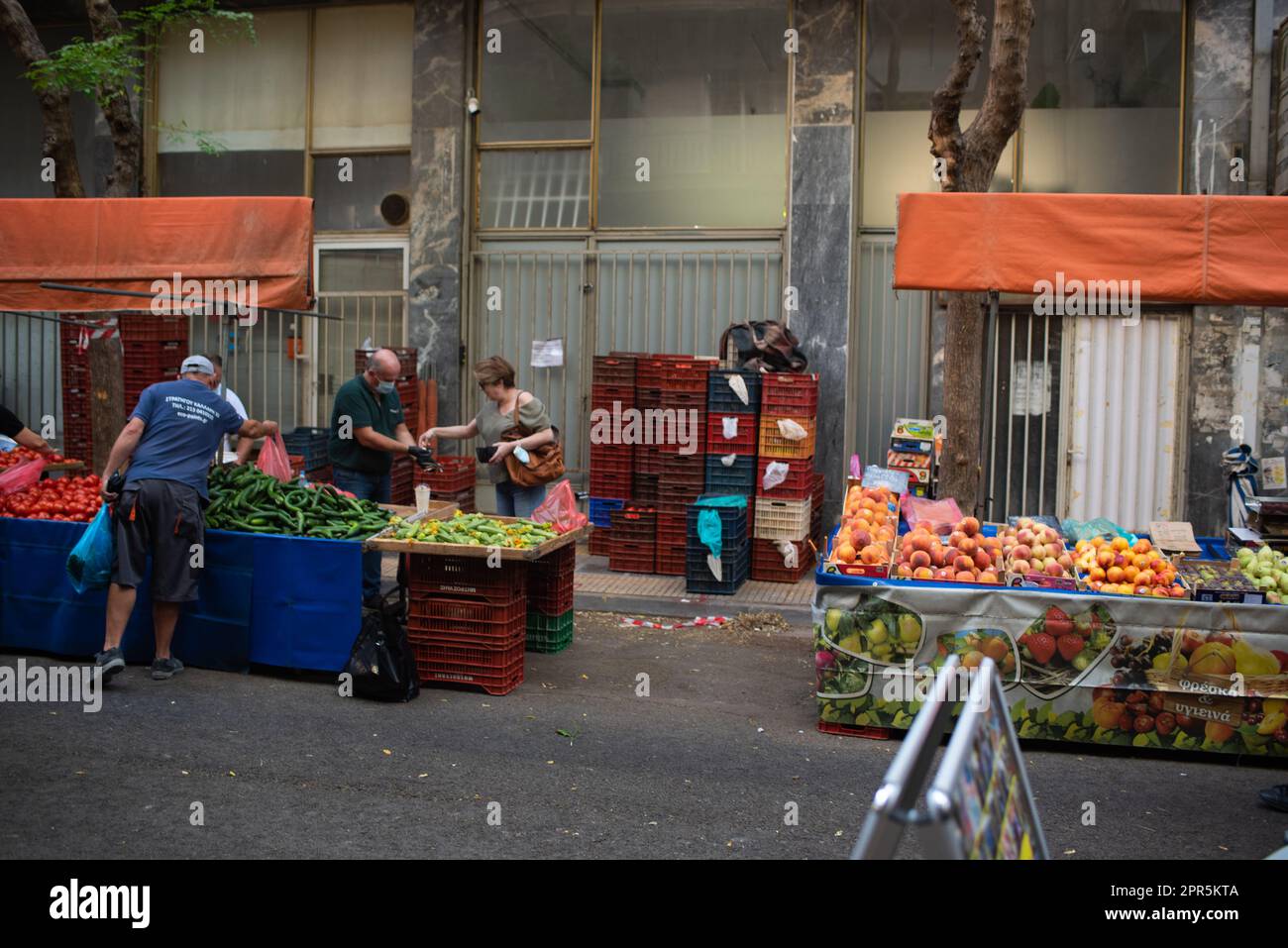 Frau bezahlt Gemüsehändler für Lebensmittel auf dem europäischen Bauernmarkt in Athen Stockfoto