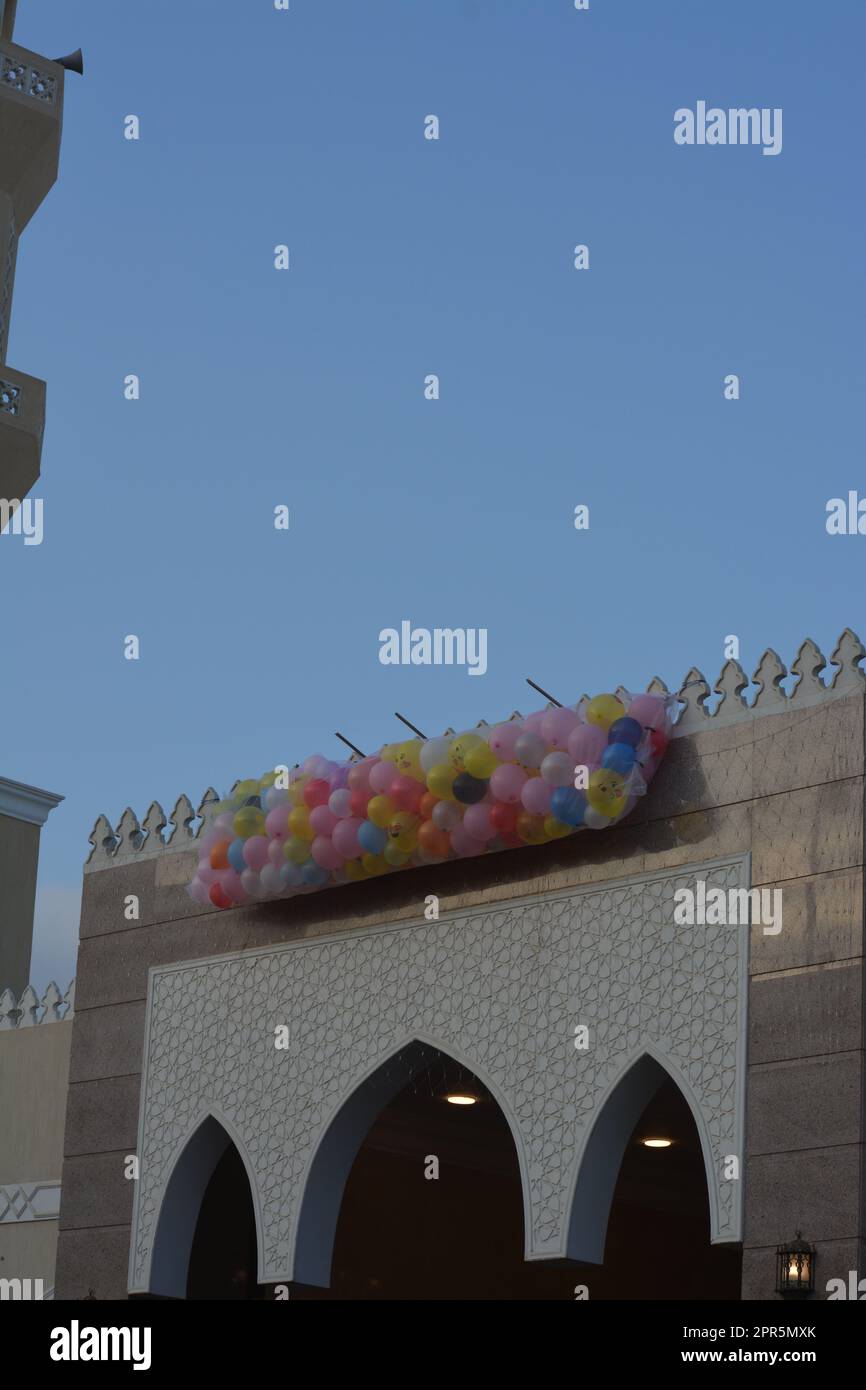 Hintergrund für Festlichkeiten und Feiern vor einer Moschee in Kairo Ägypten mit Dutzenden von Ballons auf dem Dach der Moschee neben dem Minarett, das geworfen werden soll Stockfoto