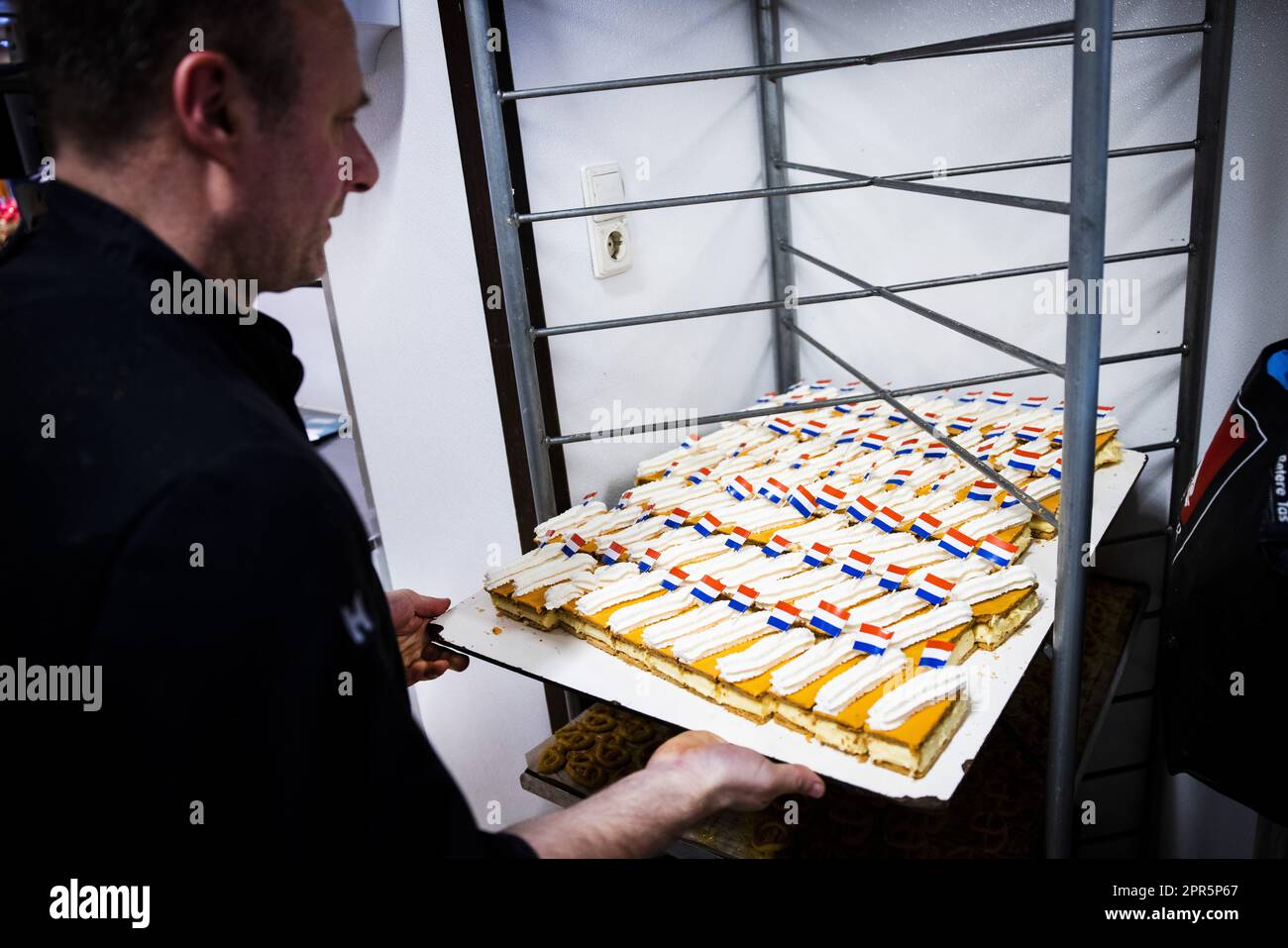 AMSTERDAM - Ein Bäcker ist damit beschäftigt, vor dem Königstag im Zentrum von Amsterdam orangefarbene Tompouces zu machen. Am Königstag sind viele Menschen in der Hauptstadt unterwegs, genau wie im Rest des Landes. ANP RAMON VAN FLYMEN niederlande raus - belgien raus Stockfoto
