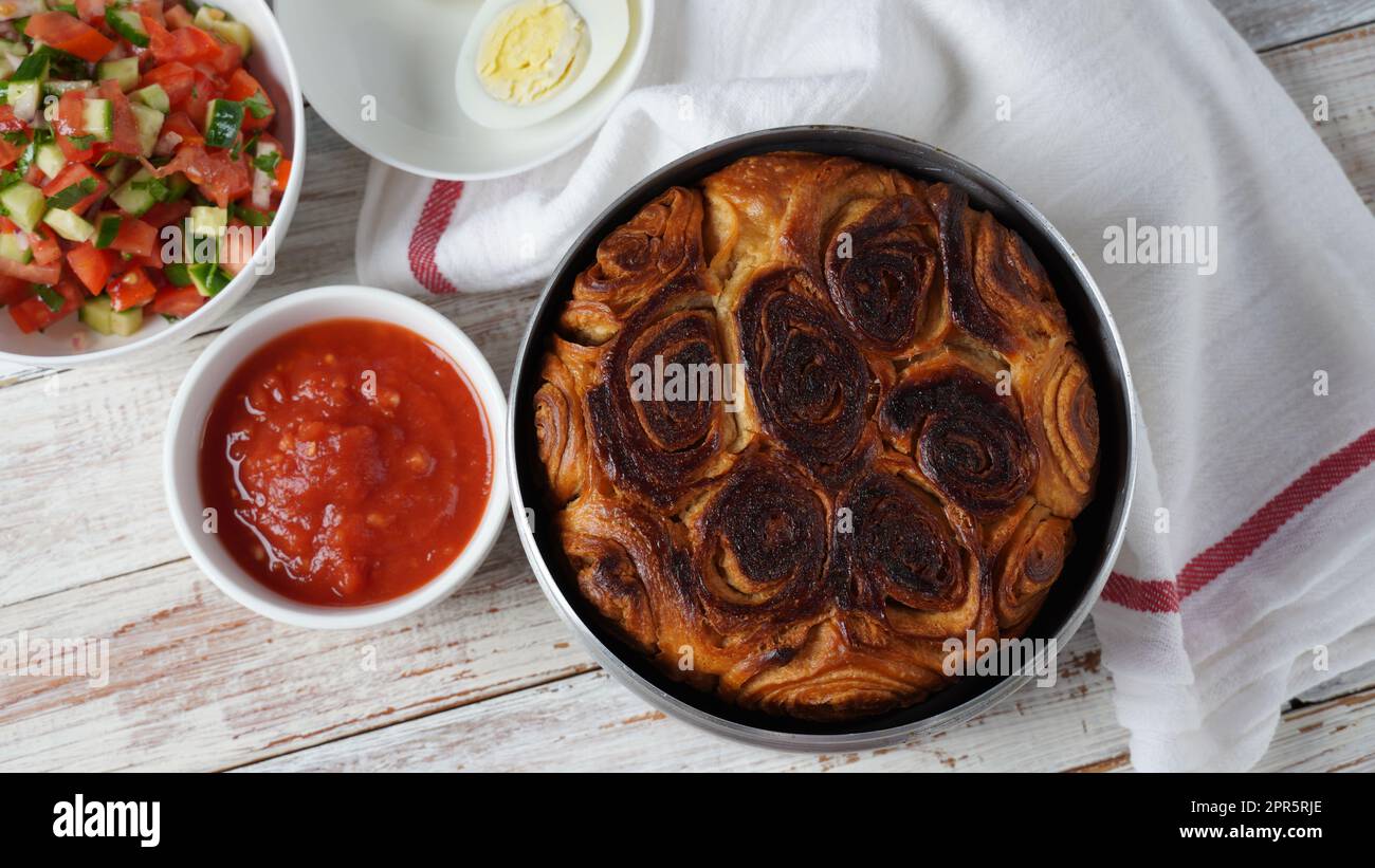 Kubaneh – Jemenitisches jüdisches Brot, Brioche-Brot – wird am Shabbat-Morgen serviert, serviert mit einem Dip aus zerkleinerten Tomaten und hart gekochten Eiern Stockfoto