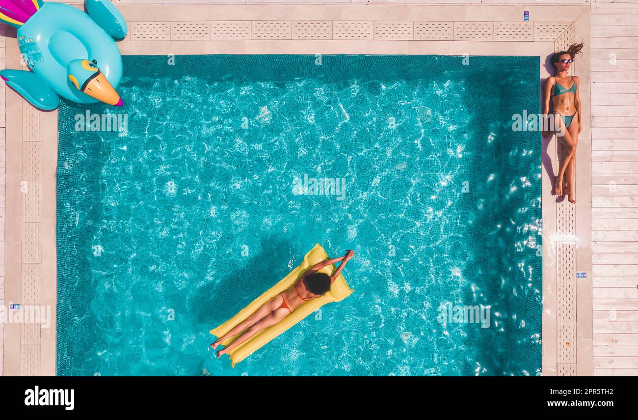 Freunde im Badeanzug, die sich in der Sonnenliege in einem Schwimmbad bräunen Stockfoto