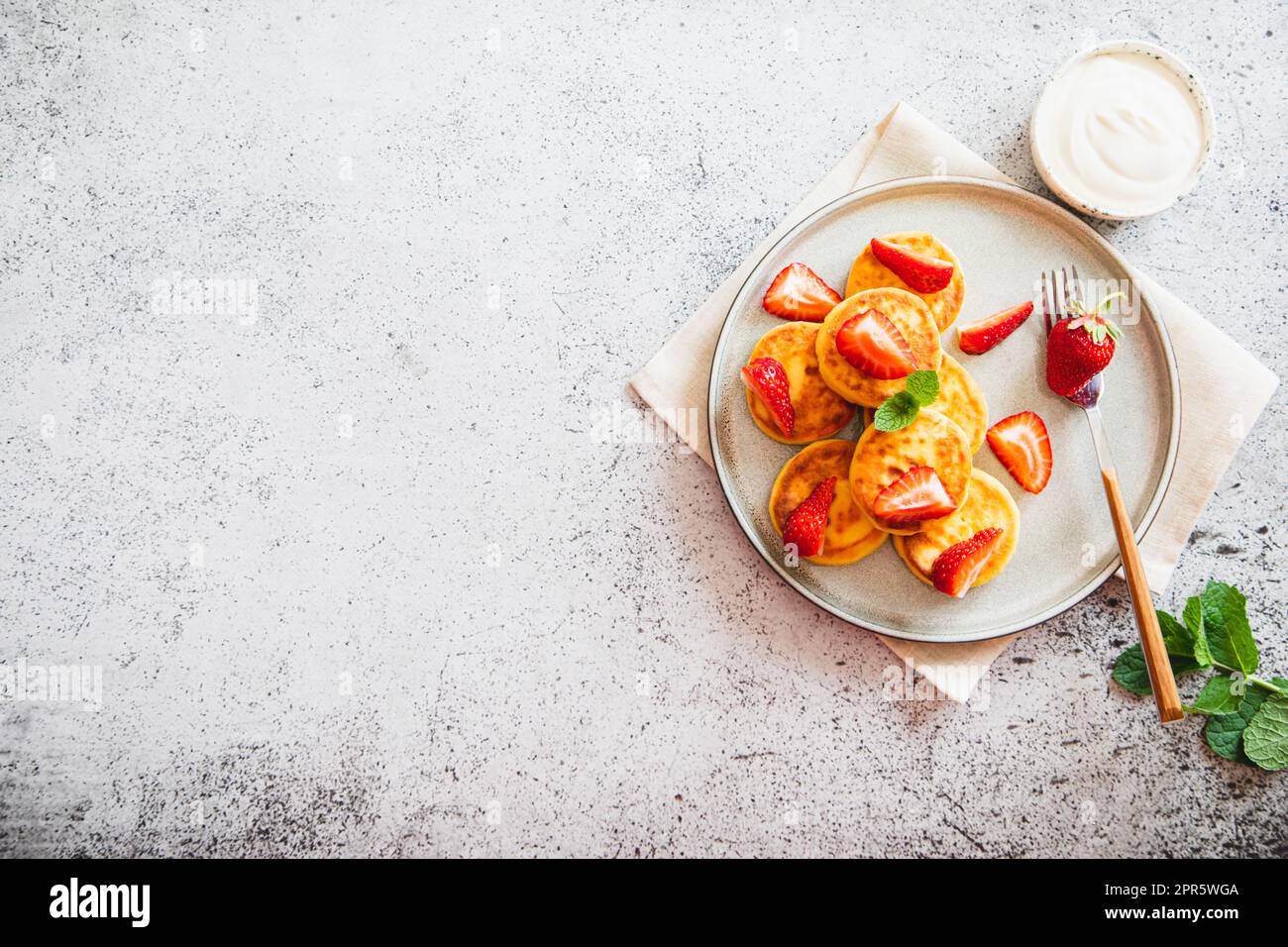 Hüttenkäse-Pfannkuchen, Ricotta-Fritters oder Syrniki mit Minze und Erdbeeren. Gesundes und köstliches Frühstück am Morgen. Stockfoto