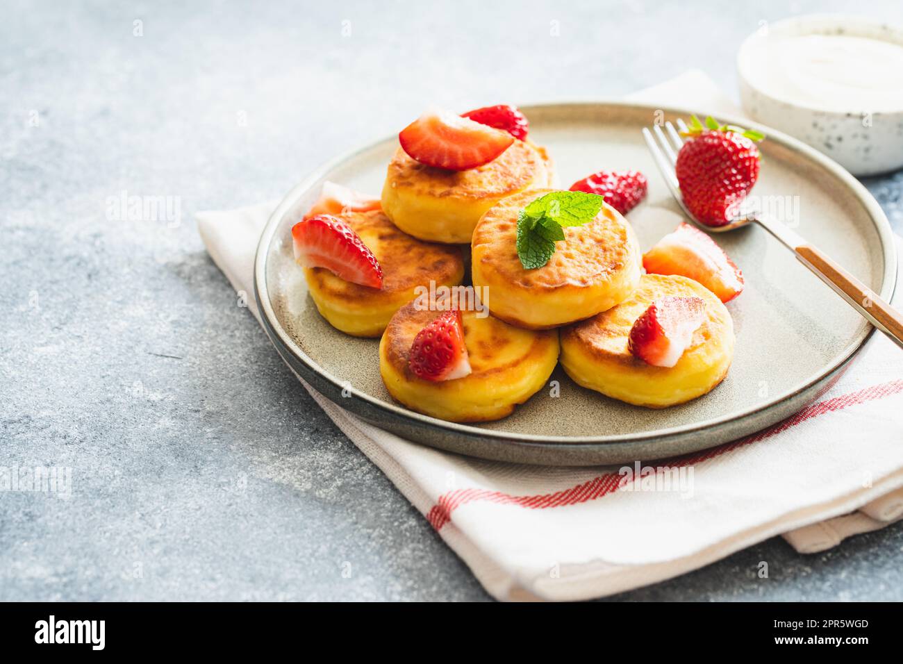 Hüttenkäse-Pfannkuchen, Ricotta-Fritters oder Syrniki mit Minze und Erdbeeren. Gesundes und köstliches Frühstück am Morgen. Stockfoto