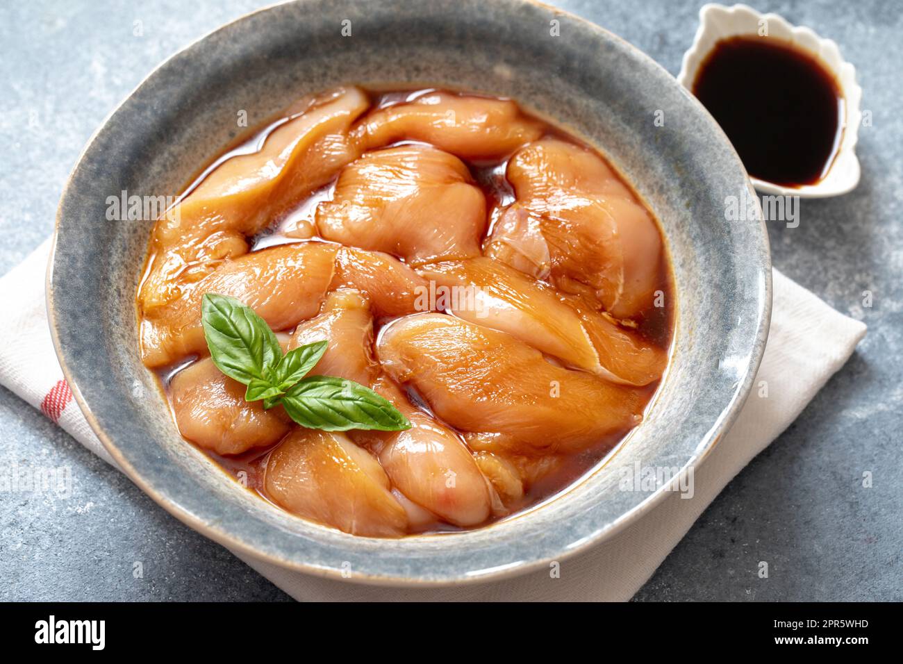 Rohkost mariniertes Hühnerfleisch mit Teriyaki-Sauce in einer grauen Schüssel. Marinieren von Fleisch zum Kochen Grill Stockfoto