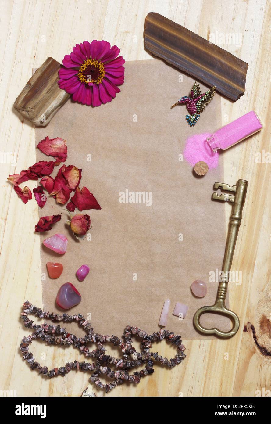 Rosafarbene Blume mit rosafarbenen Steinen und Messingschlüssel auf altem Papier Stockfoto