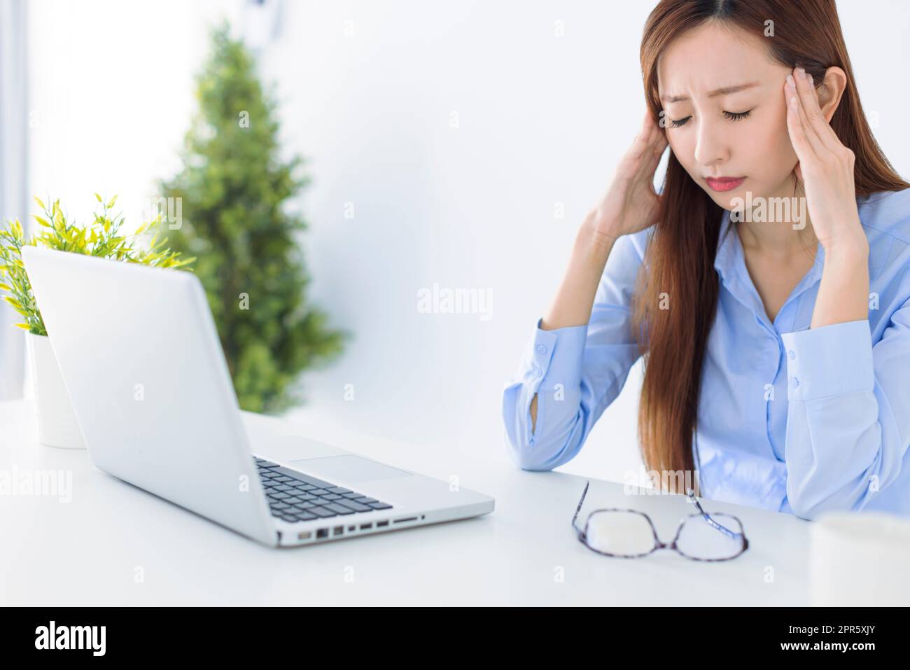 Gestresst und Kopfschmerzen Geschäftsfrau, die im Büro arbeitet Stockfoto