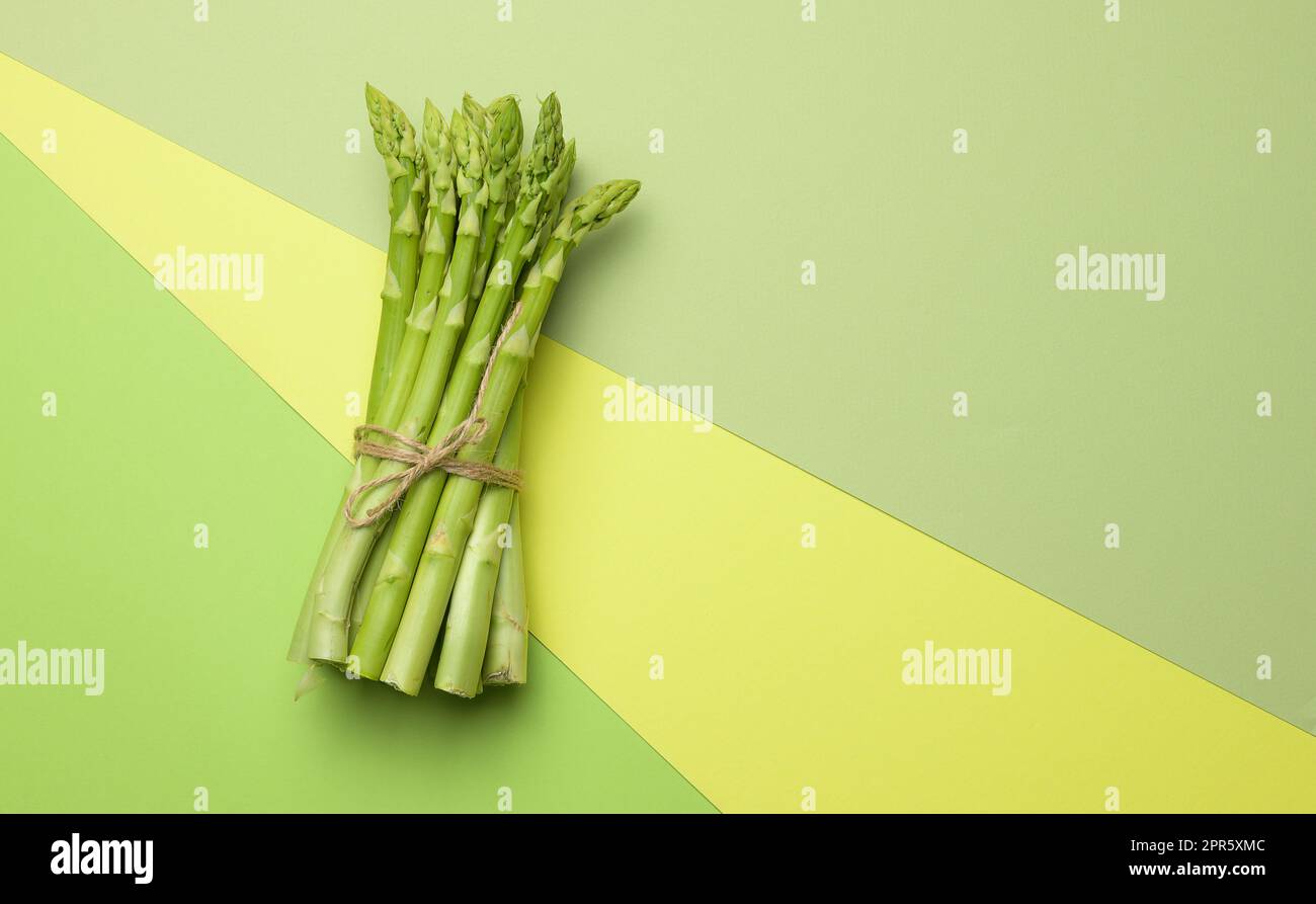 Bund frischer Spargel auf grünem Papier Hintergrund, Draufsicht Stockfoto