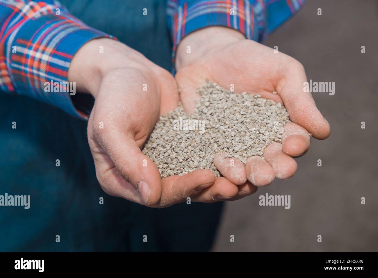 Die Hände des Bauern halten Futter, Futter für Vögel und Hühner aus nächster Nähe. Haushaltsgelände. Stockfoto