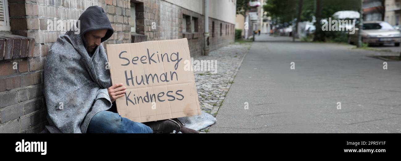 Bettler, die auf der Suche nach menschlichen Güte Zeichen auf Karton Stockfoto