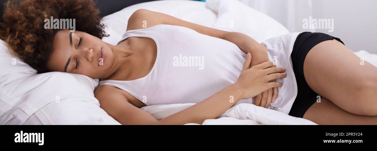 Frau mit Magenschmerzen liegend auf Bett Stockfoto