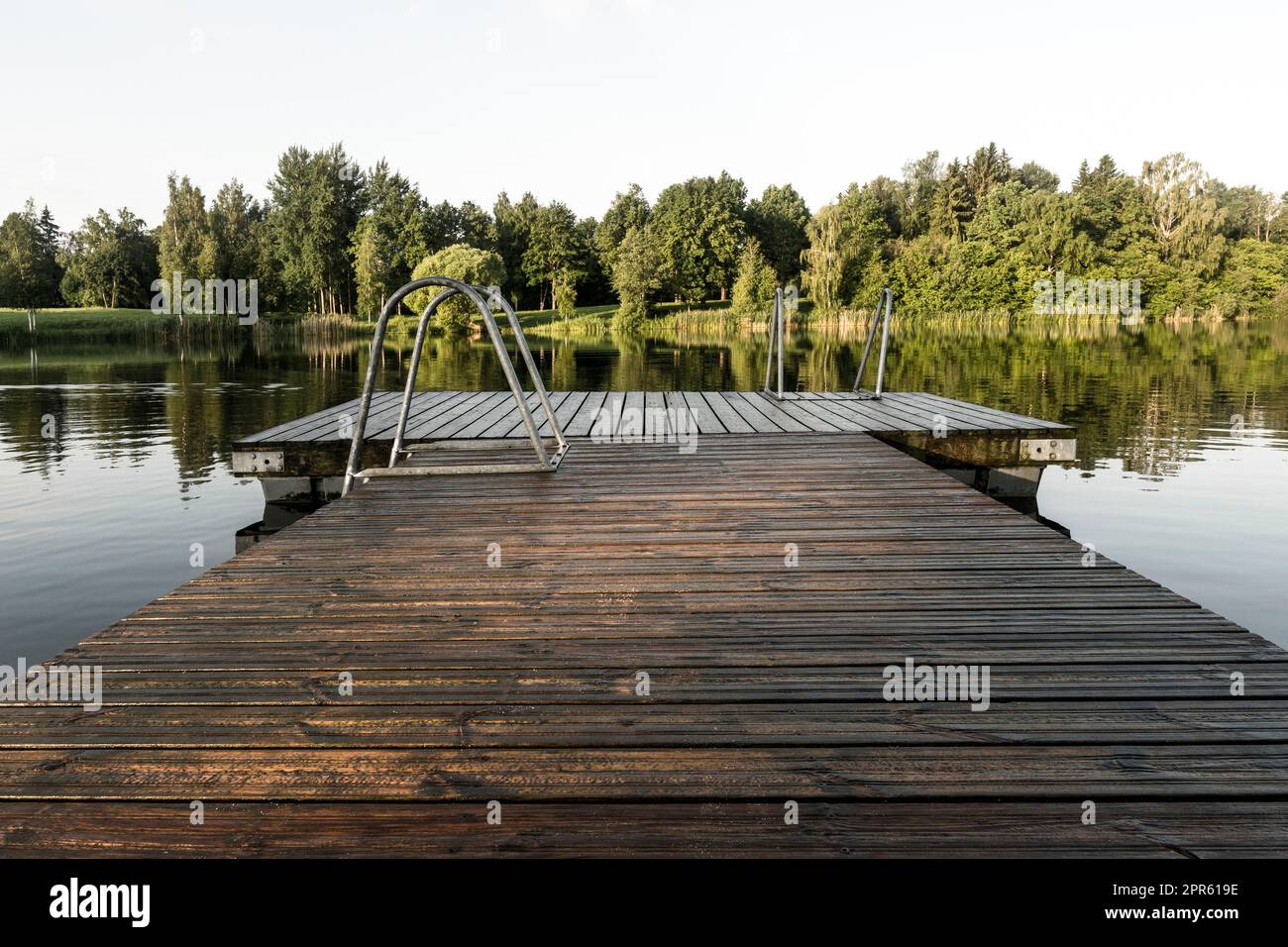 Nasser Holzpier im glatten Wasser des Sees Stockfoto