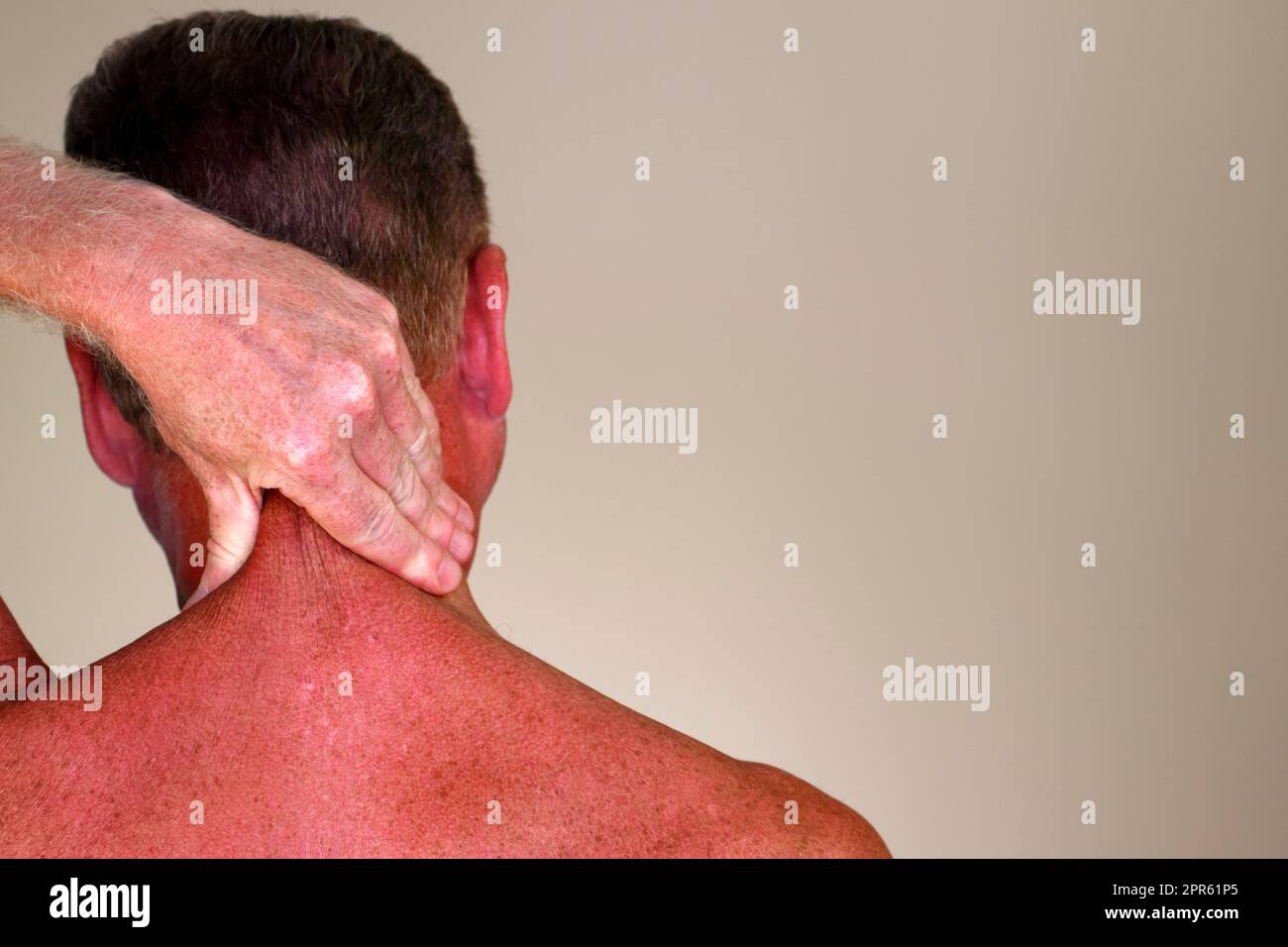 Rückansicht der linken Hand eines älteren kaukasischen Mannes mit Nackenmassage Stockfoto