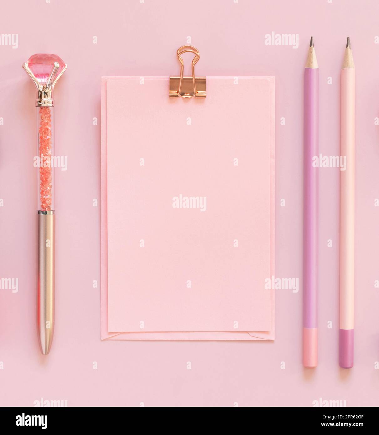 Pinkfarbene Karte mit Clip, Stift und deorativem Edelsteinstift auf hellrosa Draufsicht Stockfoto