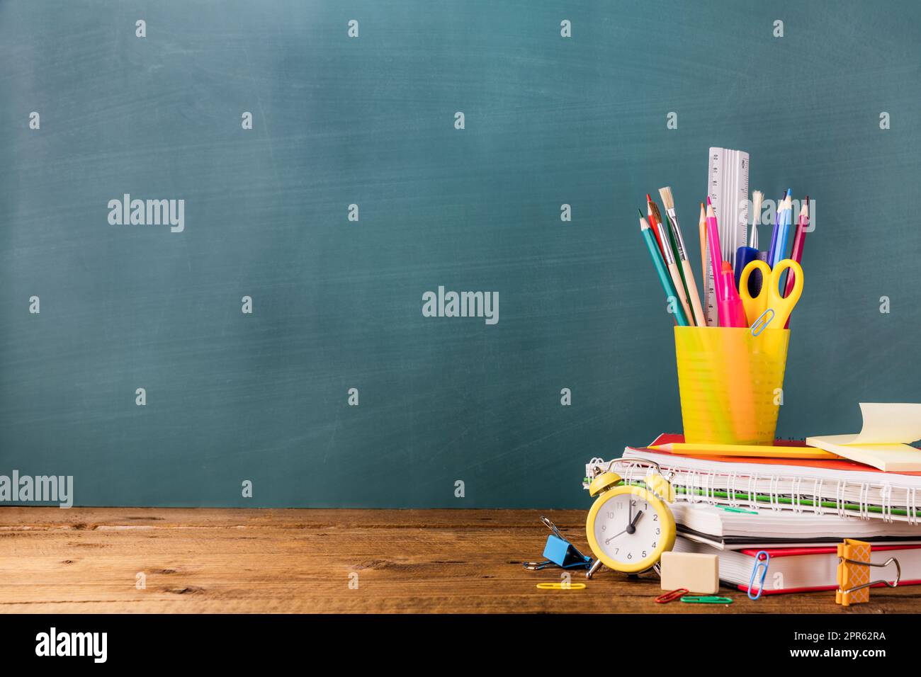 Viele verschiedene Schulen, Bürobedarf auf einem Holztisch auf grünem Hintergrund Stockfoto