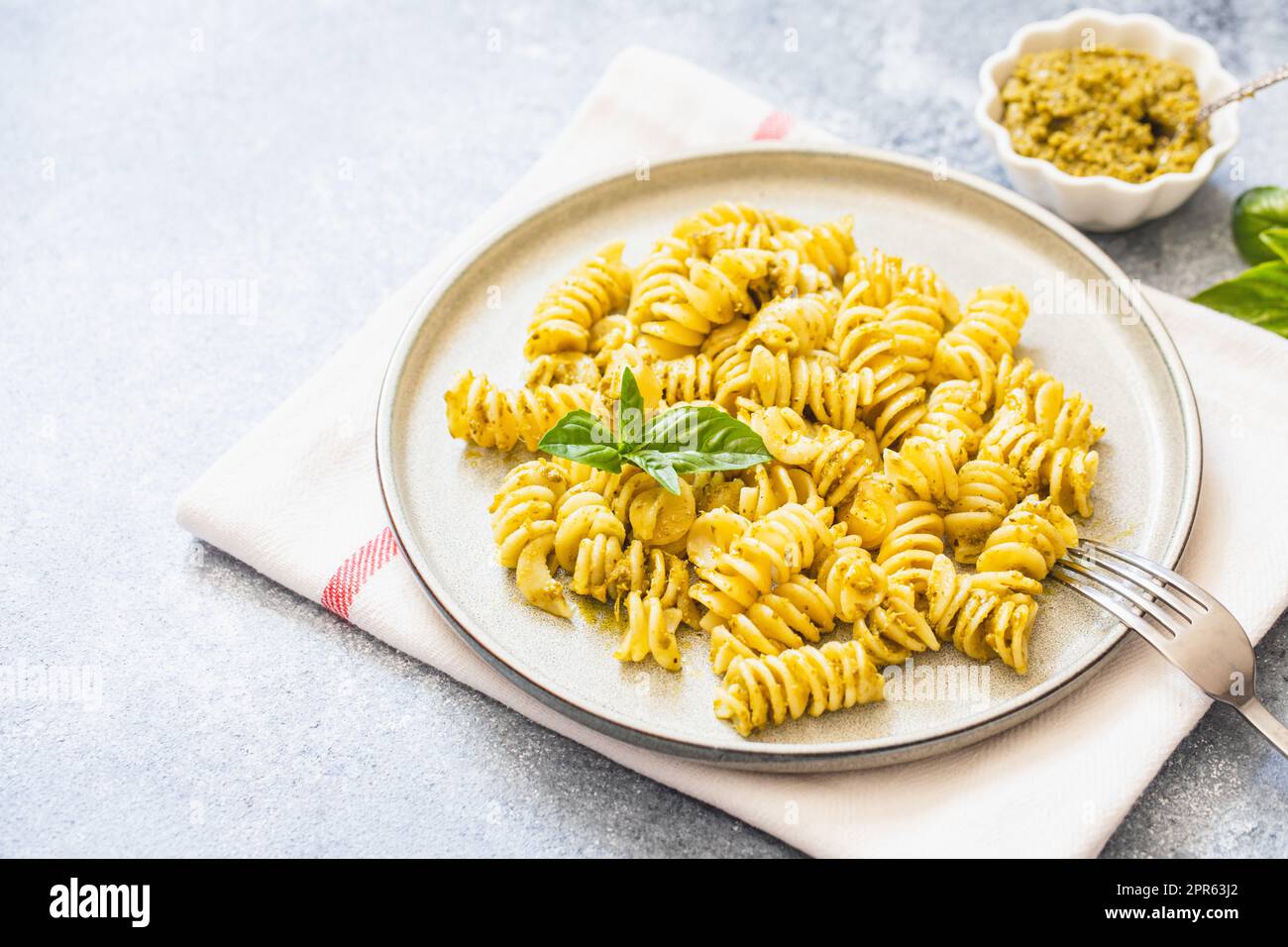 Fusili Pasta mit Basilikumpesto und Kräutern, italienische Küche, grauer Steinhintergrund. Hausgemachtes Essen. Stockfoto