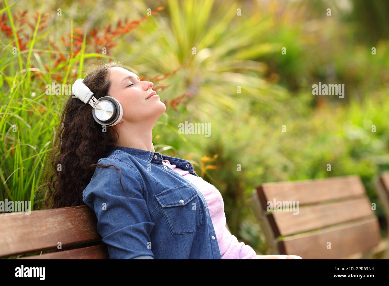 Entspannte Frau, die in einem Park Musik hört Stockfoto