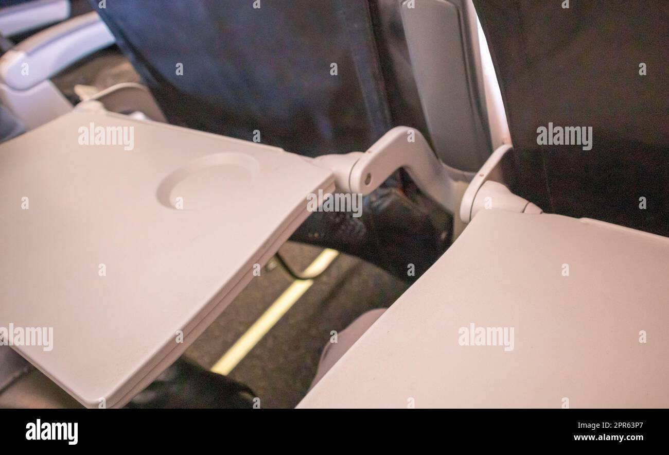 Nahaufnahme von zwei offenen Tischen für Essen in der Kabine, Draufsicht, rosa getönt. Das Konzept bequemer Flüge und Reisen Stockfoto