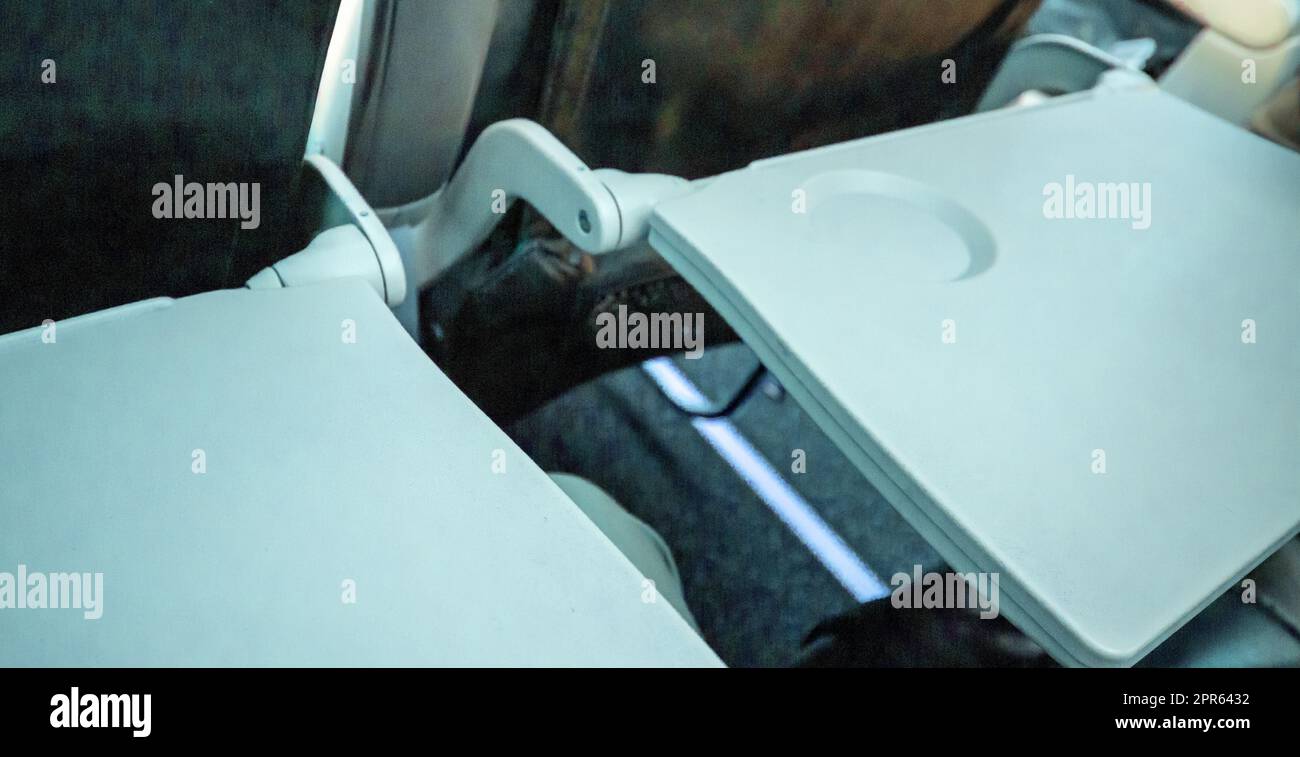 Nahaufnahme von zwei offenen Tischen für Essen in der Kabine, Ansicht von oben, blau getönt. Das Konzept bequemer Flüge und Reisen Stockfoto