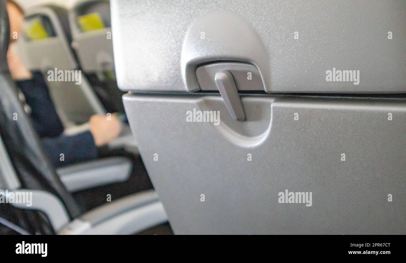 Selektiver Fokus auf einem geschlossenen Tisch, einem Tisch für Speisen in der Kabine, einem verschwommenen Hintergrund der Passagiere im Innenraum, dem Konzept bequemer Flüge und Reisen Stockfoto