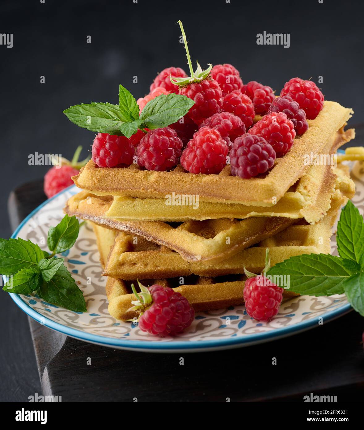 Stapel gebackener belgischer Waffeln mit reifen roten Himbeeren, grünen Minzblättern Stockfoto